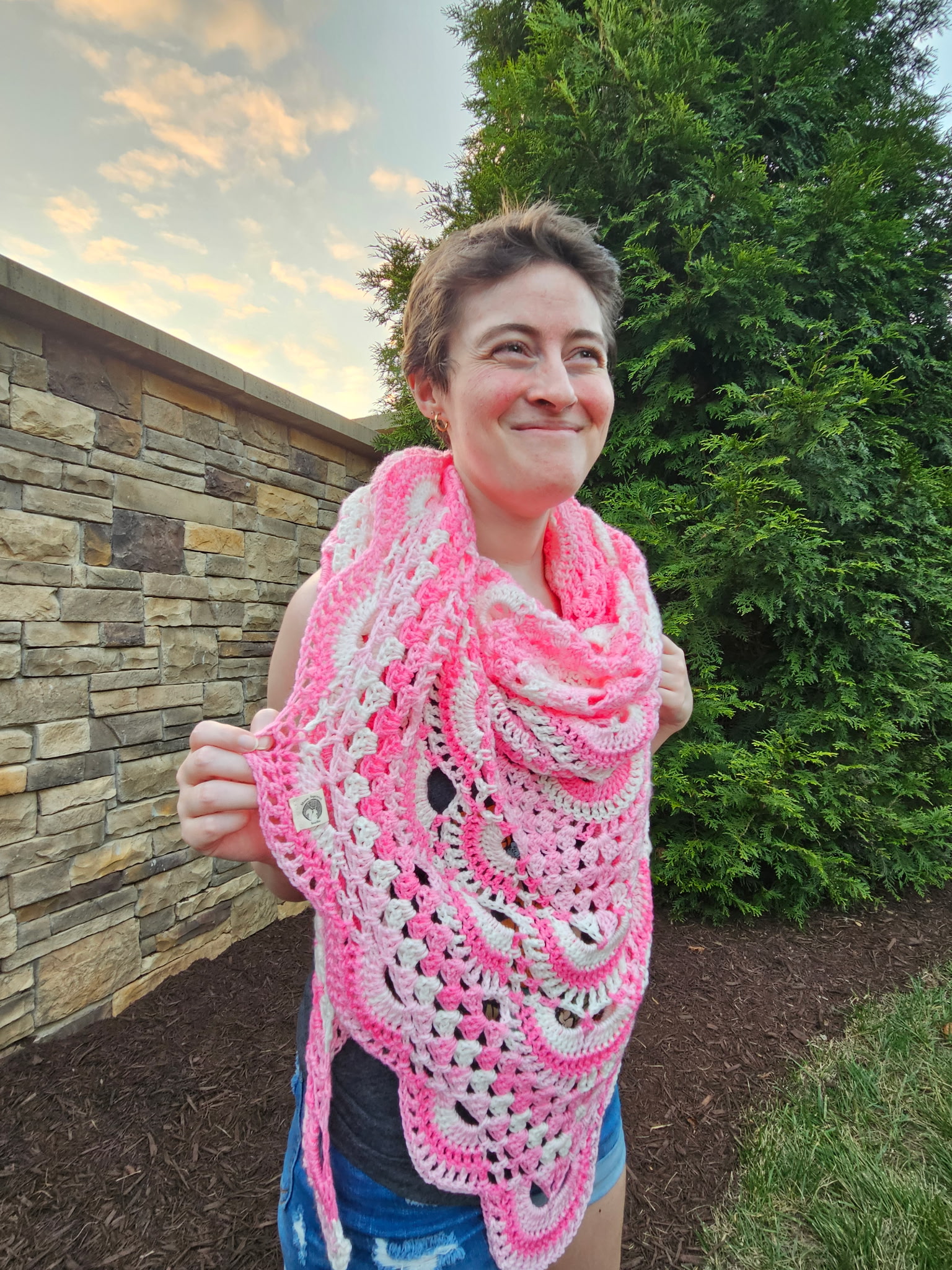 Smiling girl with short brown hair wearing a pink and white shawl as a scarf